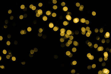 Defocused bokeh christmas small gold lights on black background. Blurred abstract gold glitter texture. Gold bokeh glitter wallpaper for Christmas, New year, festival or holiday background.