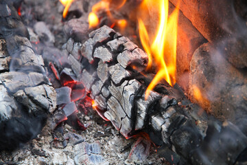 Glowing embers in hot red color, abstract background. The hot embers of burning wood log fire. Firewood burning on grill. Texture fire bonfire embers.