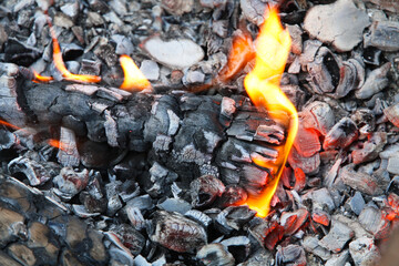 Glowing embers in hot red color, abstract background. The hot embers of burning wood log fire. Firewood burning on grill. Texture fire bonfire embers.