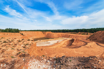 Red quarry with a huge stone in sunny summer day.