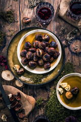 Roasted chestnuts for Christmas served on a wooden table with red mulled wine