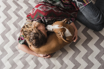 Woman lays down with a dog and hugs her. Emotional support, depression and stress relief with pets...