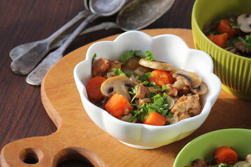 Meat stew with vegetable and mushrooms in bowl on rustic wooden background