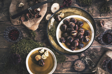 Roasted chestnuts for Christmas served on a wooden table with red mulled wine