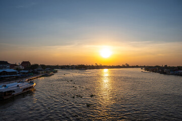 Naklejka premium NONTHABURI, THAILAND - November 14, 2020: Beautiful Sunset View of Koh Kred at Rama IV bridge cross the Chao Phraya River in Park Kred, Nonthaburi province, Thailand