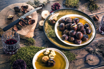 Roasted chestnuts for Christmas served on a wooden table with red mulled wine