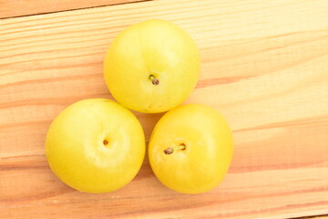 Naklejka na ściany i meble Several bright yellow plums, close-up, on a wooden table.