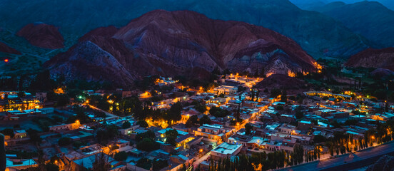 Stock photo of houses from the village of Purmamarca in Jujuy, Argentina. Landscape with colored mountains and hills in nightfall