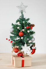 Christmas tree with decorations on wooden table and white wall background