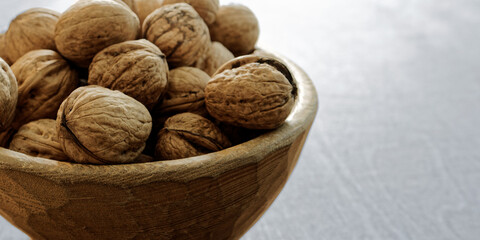 Close-up view of wooden rustic bowl with walnuts. Copy space.