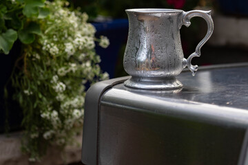 A close up of a frosty antique pewter tankard resting on a grill shelf. 