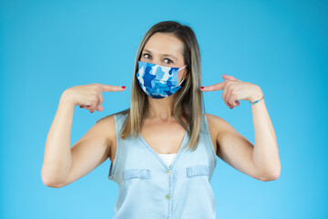 Woman in casual shirt wearing surgical mask over blue background
