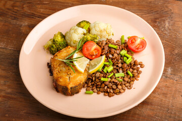 Baked fish with broccoli and lentils in a beige plate.