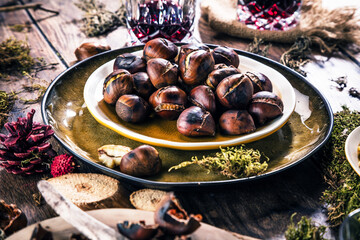 Roasted chestnuts for Christmas served on a wooden table with red mulled wine