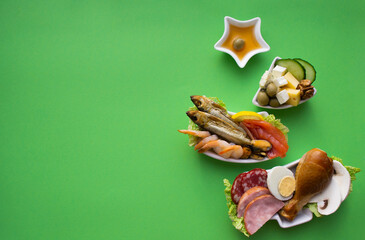Plate in the form of a Christmas tree with protein food - meat, fish, cheeses, nuts, etc. Green background. The concept of keto diet treats for the holiday. Copy space