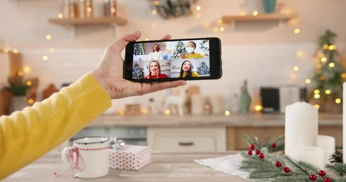 Close Up Of Smartphone Screen With Multiple Video Conference With Multi-ethnic Asian And Caucasian Women Friends And Relatives At Decorted Home In Quarantine. New Year's Eve. Merry Christmas.