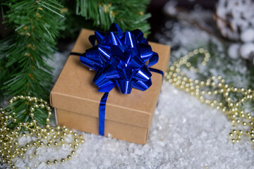 beautiful christmas gift box with a blue bow on the snow for valentine's holiday decorations and a christmas tree