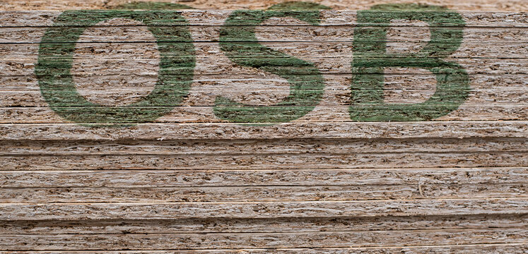 OSB sheets are stacked in a hardware store. The building material is wood.