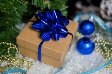 beautiful christmas gift box with a blue bow on the snow for valentine's holiday decorations and a christmas tree