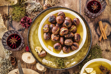 Roasted chestnuts for Christmas served on a wooden table with red mulled wine