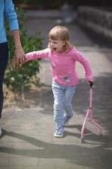 Mother holds hand of disabled daughter. Mother helps her disabled daughter to walk with sticks.