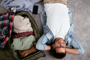 Young smiling man packing clothes into travel bag. Man preparing for the trip