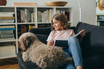 teenage girl sitting on sofa at home with her dog