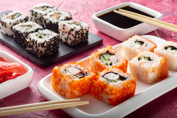 Assorted rolls on a colored background with soy sauce.