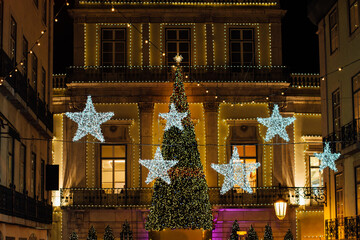 Facade of a building decorated with illumination in shape of stars and a Christmas tree during Christmas celebrations at night