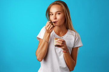 Beautiful young woman eating yogurt with a spoon