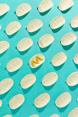 Pattern of potato chips over a cyan background with mustard
