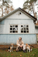 young stylish woman with two beagle dogs in the forest