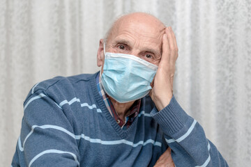 aged male person in disposable face mask sitting with hand leaning head
