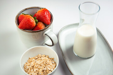 a beautiful mug of gray-blue color with strawberries, a gray-blue tray and a bowl with grains of oatmeal on a white background. horizontal photo. Frontal composition