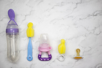 Baby accessories lie on white marble. Place for text