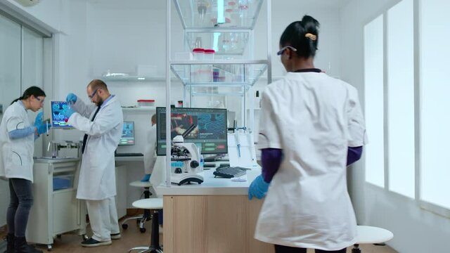 Medical multiethnic stuff testing covid19 vaccine in modern equipped laboratory. Diverse group of scientists analysing virus evolution using high tech and chemistry tools for researching treatment