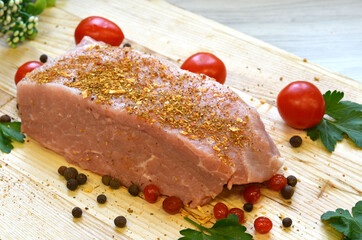 Raw pork meat on cutting board and vegetables and greens