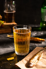 Glass of beer and fish on the black table