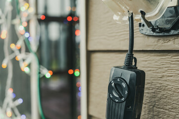 Outdoor timer and GCFI outlet with cover. Blurred christmas lights in background.