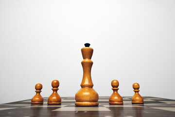 Chessboard with wooden figures against grey background