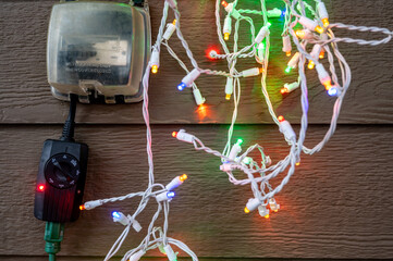 Outdoor timer and GCFI outlet with cover. Blurred christmas lights in background.
