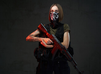 Dressed in dark armour and shirt female soldier with short haircut and weared with mask poses...