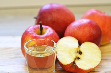 Apple cider vinegar in glass bottle and fresh apples on wooden background