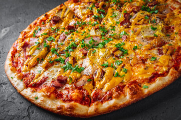 Pizza with Mozzarella cheese, backon, ham, tomato sauce, pepper, sausage, pickled cucumbers and onion. Italian pizza on Dark grey black slate background