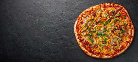 Pizza with Mozzarella cheese, backon, ham, tomato sauce, pepper, sausage, pickled cucumbers and onion. Italian pizza on Dark grey black slate background