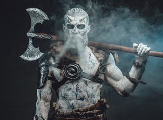 Risen from the dead northern warrior in smokey background with huge two handed axe on his shoulders...