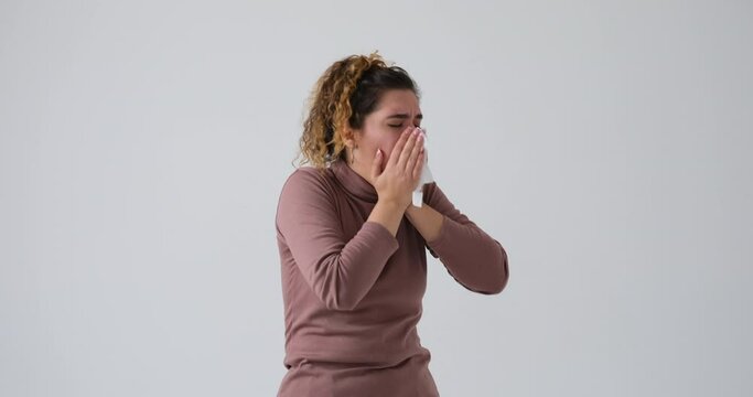 Sick woman coughing and covering mouth with tissue paper