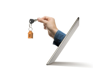 Key with paper house in human hand stick out of a digital tablet screen. Concept of modern technologies in real estate industry.