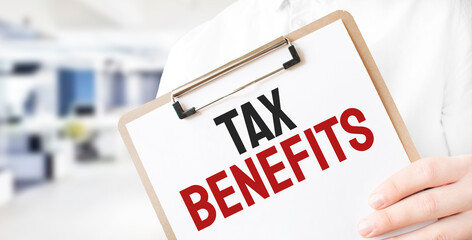 Text TAX BENEFITS on white paper plate in businessman hands in office. Business concept