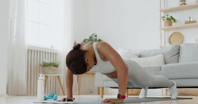 Young african american woman trying to do push ups, lying down and laughing